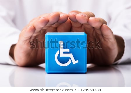 Foto stock: Human Protecting Cubic Block With Disabled Handicap Icon