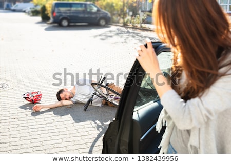 Stok fotoğraf: Woman Looking At Unconscious Male Cyclist Lying On Street