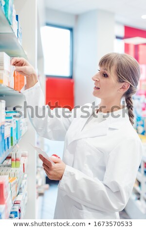 Foto d'archivio: Pharmacist Or Chemist Woman Sorting Drugs In Shelves In Her Pharmacy