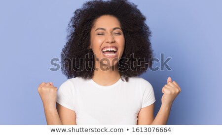 Stockfoto: Overjoyed African American Woman Clenches Fists With Triumph Laughs With Happiness Rejoices Succes