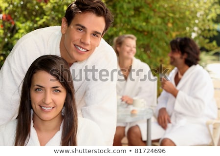 Stockfoto: Two Couple Sat In Garden Wearing Dressing Gowns