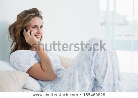 Foto stock: Attractive Woman Sitting In Bed And Talking On Cellphone