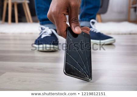 Stock photo: Man Picking Up Damaged Mobile Phone