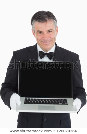 Foto stock: Smiling Waiter Showing Us Something On A Laptop In Front Of Camera