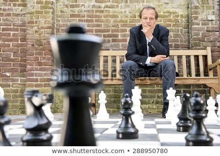 Foto stock: Thinking Man Sitting At A Life Sized Outdoor Chess Board