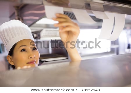 Foto d'archivio: Female Chef Looking At An Order List In The Commercial Kitchen