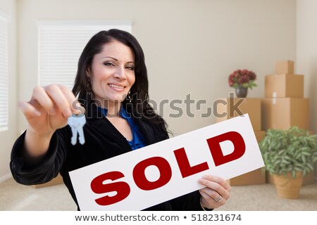 Foto stock: Hispanic Woman With House Keys And Sold Real Estate Sign In Empt