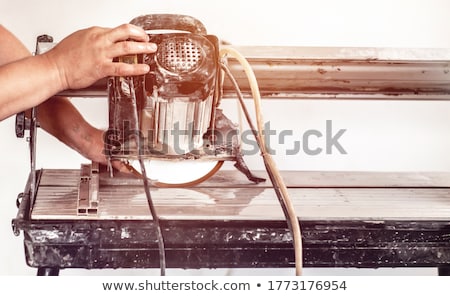 Stock foto: Worker Using Wet Tile Saw To Cut Wall Tile At Construction Site