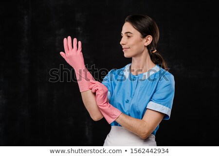 Stok fotoğraf: Pretty Young Hotel Room Service Staff In Blue Uniform Putting On Rubber Gloves