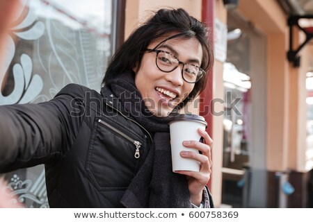 Foto stock: Cheerful Young Asian Man Drinking Coffee And Make Selfie