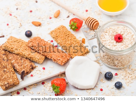 Stok fotoğraf: Organic Cereal Granola Bar With Berries On Marble Board With Honey Spoon And Jar Of Oats And Coconut