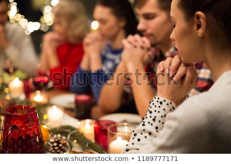 Foto stock: Close Up Of Friends Praying At Christmas Dinner