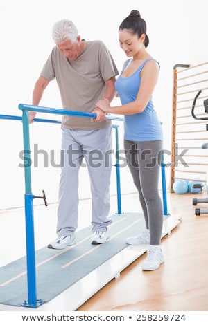 [[stock_photo]]: Physiotherapist Helping Senior Man In Rehabilitation Walking On The Bars