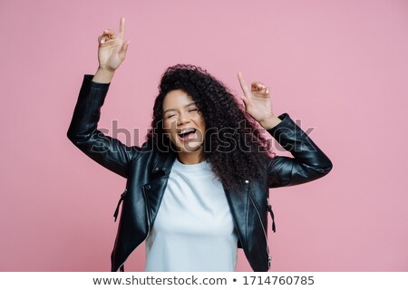 [[stock_photo]]: Carefree Beautiful Afro American Woman Dances With Arms Raised Moves With Rhythm Of Music On Disco