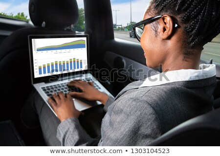 Zdjęcia stock: Businesswoman Sitting Inside Car Examining Graph On Laptop