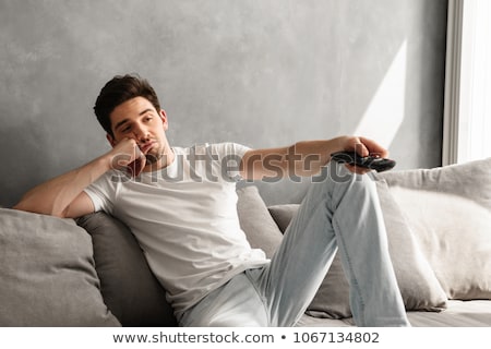 Foto d'archivio: Photo Of Young Bored Man Sitting On Couch At Home And Changing