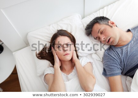 Foto stock: Woman Looking At Man Snoring In Bed