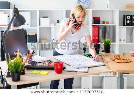 Сток-фото: A Young Girl Is Talking On The Phone Holding A Marker In Her Hand And Standing Near The Board With