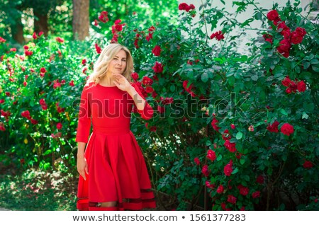 Foto stock: Cute Girl In A Long Dress Walking Through The Park With Flowers In Hands