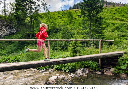 Zdjęcia stock: Young Woman Running On Bridge In Mountains On Summer Day