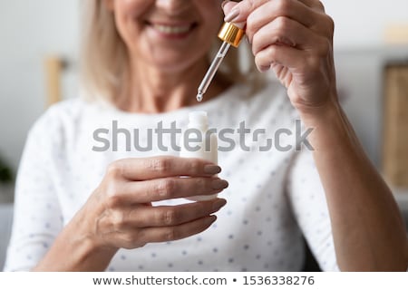 Stok fotoğraf: Smiling Senior Woman With Bottle Of Serum