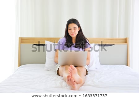 Stock fotó: Woman Relaxing On Her Bed With A Laptop