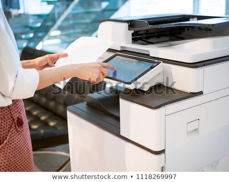 Foto stock: Young Man Employee Working At Copying Machine In The Office