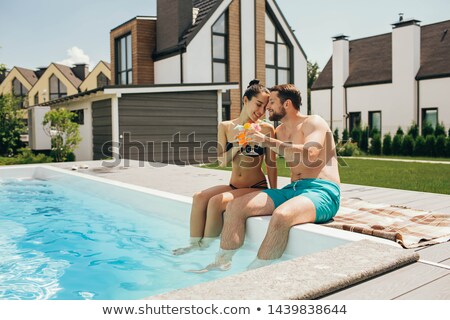 Foto stock: Smiling Woman Sitting In Bikini Near Swim Pool