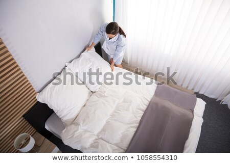 Stock fotó: Housekeeper Arranging Bedsheet On Bed