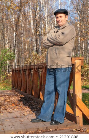 Stockfoto: Portrait Of Elderly Man In Black Hat In Wood In Autumn On Wooden Bridge