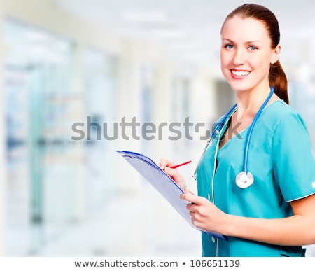 Foto stock: Smiling Medical Doctor With Clipboard In A Corridor Of A Hospita