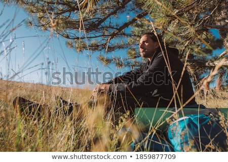 Сток-фото: Young Caucasian Man With Backpack Sitting On The Top Of Hill