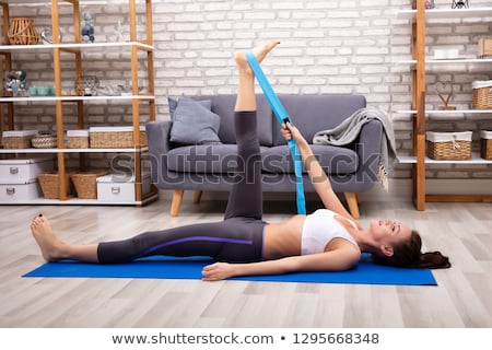 Foto stock: Woman Using Yoga Belt While Doing Exercise