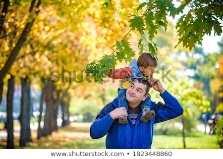 Stock foto: Happy Father Carrying Son With Autumn Maple Leaves