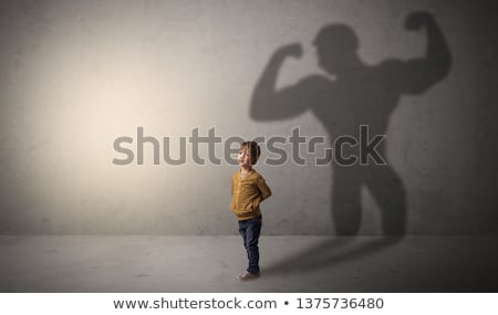 Foto stock: Muscleman Shadow Behind Waggish Little Boy