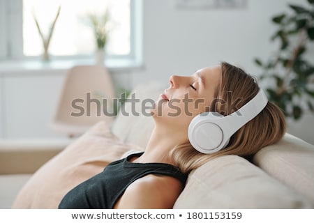 Foto d'archivio: Beautiful Woman At Home Lying Down Enjoying Music