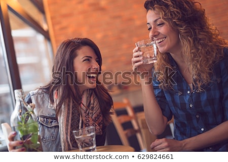 Stock foto: Two Happy Attractive Young Women Drinking Water In Cafe