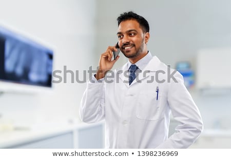 Stock foto: Smiling Indian Male Doctor Calling On Smartphone