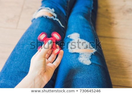 Stok fotoğraf: Girl Teenager In Holey Jeans Holds In Hands And Plays With Spinner