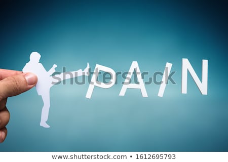 Foto stock: Human Hand Holding Human Figure Kicking White Pain Word