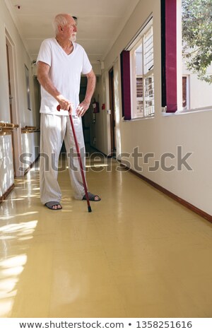 Stockfoto: Front View Of Senior Caucasian Male Patient Standing With Stick In Corridor At Retirement Home