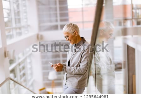[[stock_photo]]: Senior Businesswoman Using Mobile Phone In Modern Ofice