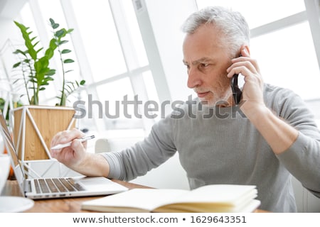 ストックフォト: Photo Of Serious Mature Man Working With Laptop And Cellphone