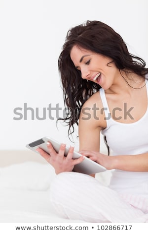 Foto d'archivio: Pretty Young Woman Using Her Tablet Computer In Bed