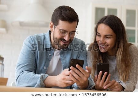 Stok fotoğraf: Young Couple Using Smartphones Together