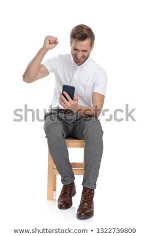 Stock fotó: Seated Casual Man Reading Good News On His Mobile Phone