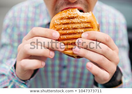 Foto d'archivio: Unrecognizable Man Eating Delicious Hamburger With Grilled Bread