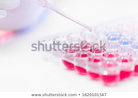 Stock photo: Pipette With Drop Of Vaccine Over Set Of Plastic Cells With Red And Blue Fluids