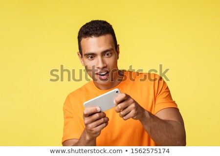 Zdjęcia stock: Excited Handsome Young Male Student Waste Time Playing Cool New Game Holding Smartphone Horizontall