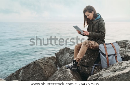 Foto stock: Woman Sitting On Stone Near Water